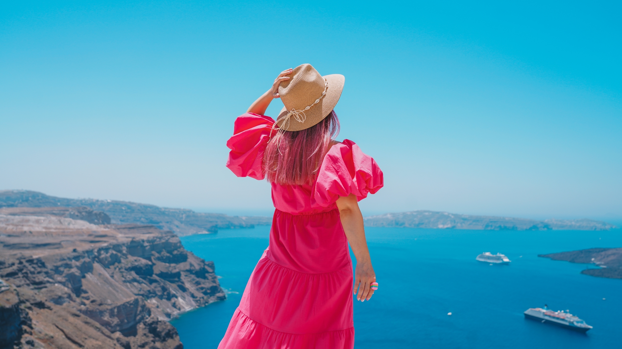 Woman in pink dress overlooking Mediterranean sea